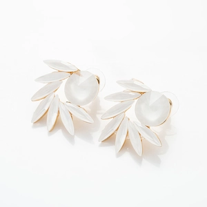 Détail de boucles d'oreilles pétales blanc cassé avec centre rond et cadre doré fin