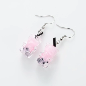 Detail of pink resin bear milk tea cup drop earrings with black straw and pearl accents