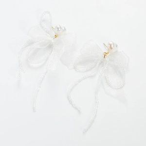 Detail of white heart pearl earrings with sheer ribbon bow and beaded trim edge