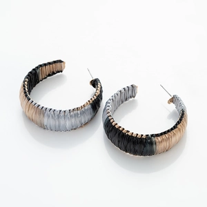 Detail of C-shaped hoop earrings featuring tricolor woven raffia in black, grey and beige