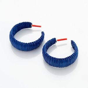 Detailed close-up of dark blue woven raffia C-shaped hoop earrings with texture