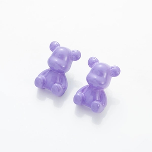 Macro view of purple resin teddy bear earrings with a smooth translucent finish