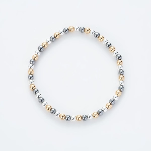 Detalle de pulsera de cuentas metálicas tricolores en tonos oro, plata y gris plomizo