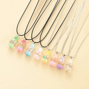 Detailed close-up of colorful liquid driftwood bottle pendants with glitter on a soft texture
