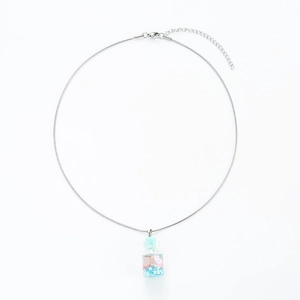 Macro detail of silver drifting bottle pendant with pink flowers and blue sequins