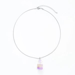 Close-up of silver chain necklace with a mini glass bottle pendant filled with purple stars