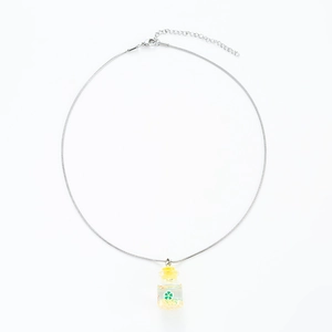 Macro detail of drift bottle pendant necklace with green floral design and silver snake chain