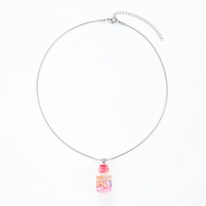 Detailed macro of a silver snake chain necklace with a pink sand glass bottle pendant