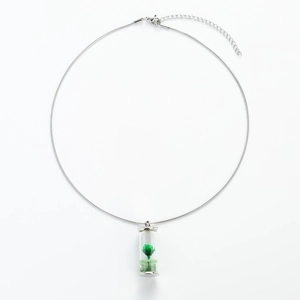 Dettaglio collana a catena serpente argento con un piccolo fiore secco verde in fiala