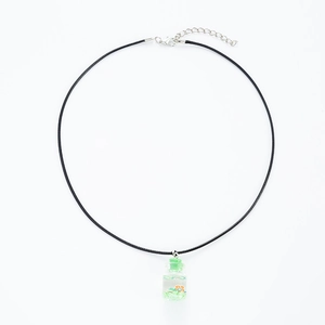 Close-up of drifting bottle necklace with green filler and orange flower pendant