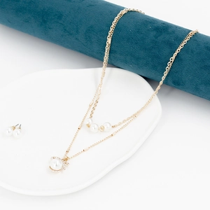 Detailansicht von Perlenhalskette und Ohrring-Set mit Goldschleife auf Samtaufsteller