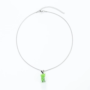 Close-up of silver metal chain with a green resin bear pendant on a white background