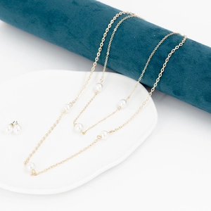 Elegantes Set aus goldener Perlenkette und Ohrringen auf einer Schmuckrolle