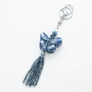 Macro detail of blue crystal butterfly pendant with beaded tassels and silver key ring