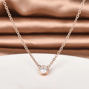 Rose gold necklace with a single round diamond pendant on a brown satin background