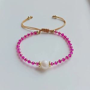 Detailaufnahme des handgemachten Perlenarmbands mit rosa Kristallen und weißer Perle