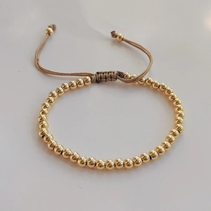 Detail der Goldperlen-Armband mit verstellbarer brauner Schnur und polierter Oberfläche