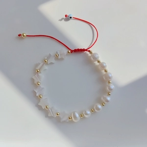 Detailansicht eines handgemachten roten Perlenarmbands mit Perlmutt-Seestern-Anhängern