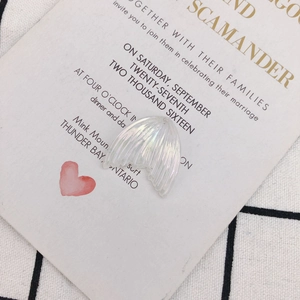 Primer plano de accesorio de cola de pez de resina iridiscente en tarjeta de invitación