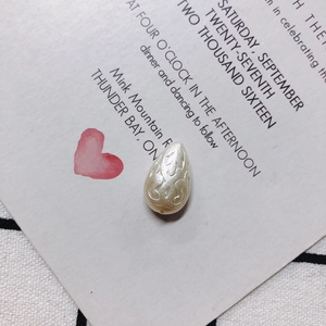 Detalle de perla acrílica en forma de gota con relieve sobre tarjeta de invitación rosa