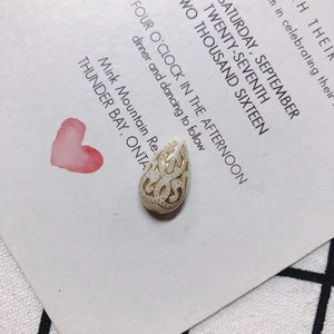Detalle de cuenta de acrílico en forma de gota con patrón de relieve dorado vintage