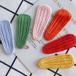 Detail of 6 colorful knitted hair clips with V-shape texture on a checkered background