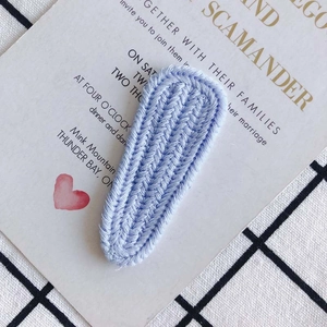Detailed view of light blue knitted BB hair clip with textured vertical yarn patterns