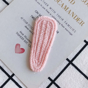 Close-up of handmade pink knitted BB hair clip with detailed V-shaped woven texture