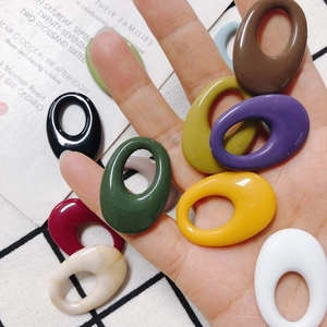 Colorful oval resin charms for DIY earrings shown in hand for size visualization