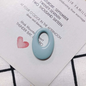 Macro detail of a light blue oval resin pendant with central hole on a decorative card