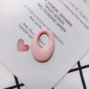 Detailed view of light pink oval resin earring link on romantic invitation backdrop