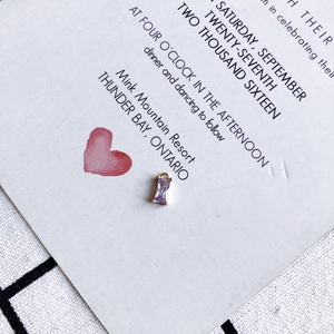 Macro shot of purple rectangular crystal pendant with gold plating on white card