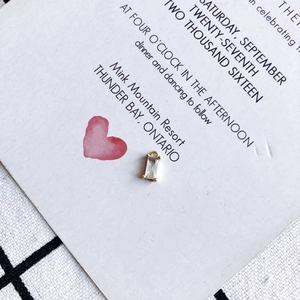 Detail shot of a rectangular crystal pendant with gold plating on a wedding invite card