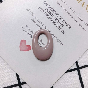 Detailed view of dusty pink oval resin pendant with glossy finish on a white card