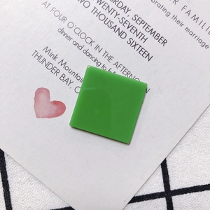 Close-up of a green square resin jewelry component on a heart print invitation card