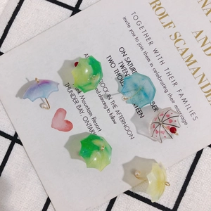 Close-up of six colorful resin umbrella charms with pearls on vintage card background