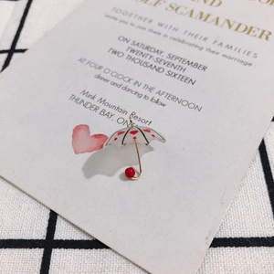Detail of a resin umbrella charm with red hearts, gold handle and small red bead