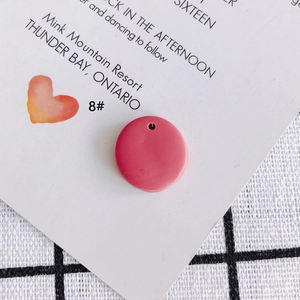 Nahaufnahme eines runden dunkelrosa Polymer-Anhänger mit Loch für DIY Schmuckherstellung