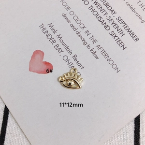 Détail macro du pendentif œil maléfique doré montrant la taille 11x12mm sur une carte