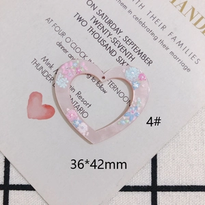 Dettaglio macro del ciondolo in resina a forma di cuore con fiori secchi, 36x42mm