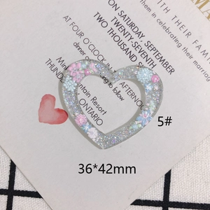 Dettaglio macro del ciondolo a cuore in acrilico glitterato con mini fiori, 36x42mm