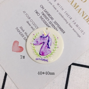 Detail of round acrylic unicorn charm with floral wreath and perforation for DIY jewelry