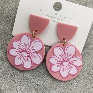 Dettaglio di orecchini a fiori rosa opaco con perni in argento 925 su espositore