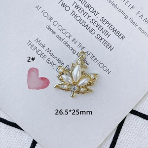 Detail of gold maple leaf charm with pearls and rhinestones on a white card