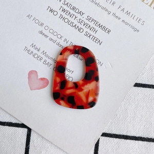 Macro-detail van rood en zwart acetaat hanger met luipaardprint en holle rechthoekige vorm