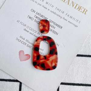Detailopname van acetaat oorbelhangers met luipaardprint op decoratieve kaart