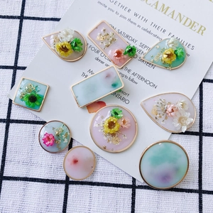 Dettaglio di ciondoli in resina con fiori secchi e foglia d'oro in varie forme geometriche
