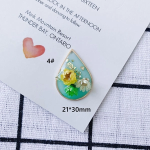 Dettaglio del ciondolo in resina a goccia con fiori secchi, farfalla d'oro e 21x30mm