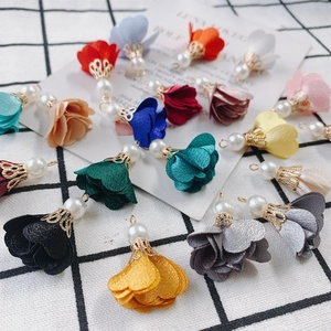Macro view of multi-color fabric flower charms with pearl accents for DIY jewelry