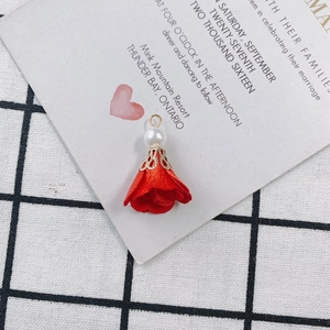Detail of red fabric flower pendant with white faux pearl and golden ring connector